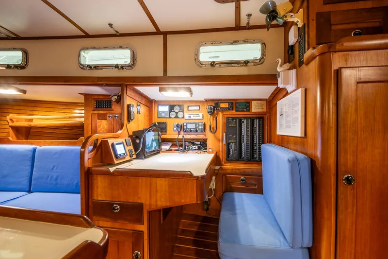 Slide: The Image of Interior of a 1997 Valiant 42 sailboat with navigation station and blue seating. - 17