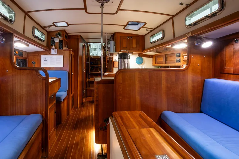 Slide: The Image of Interior of a 1997 Valiant 42 sailboat with wooden finishes and blue seating. - 34