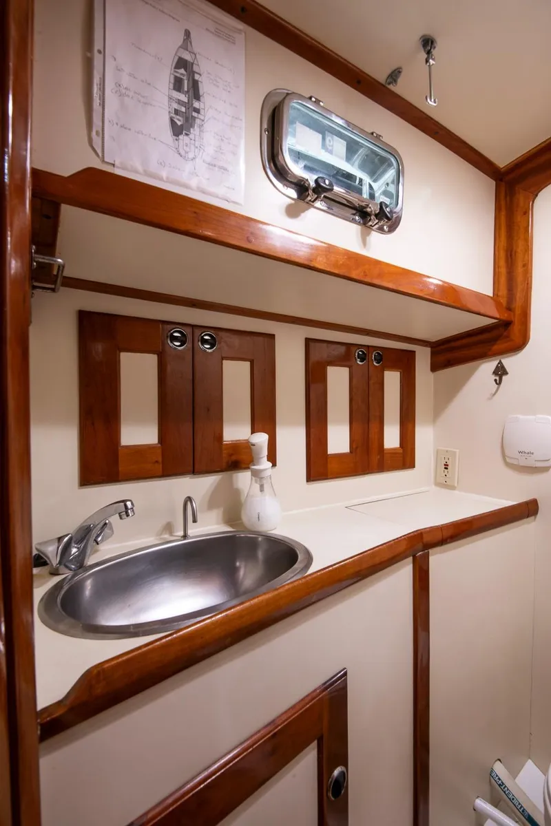 Slide: The Image of 1997 Valiant 42 yacht bathroom with wooden cabinets, stainless steel sink, and porthole window. - 36