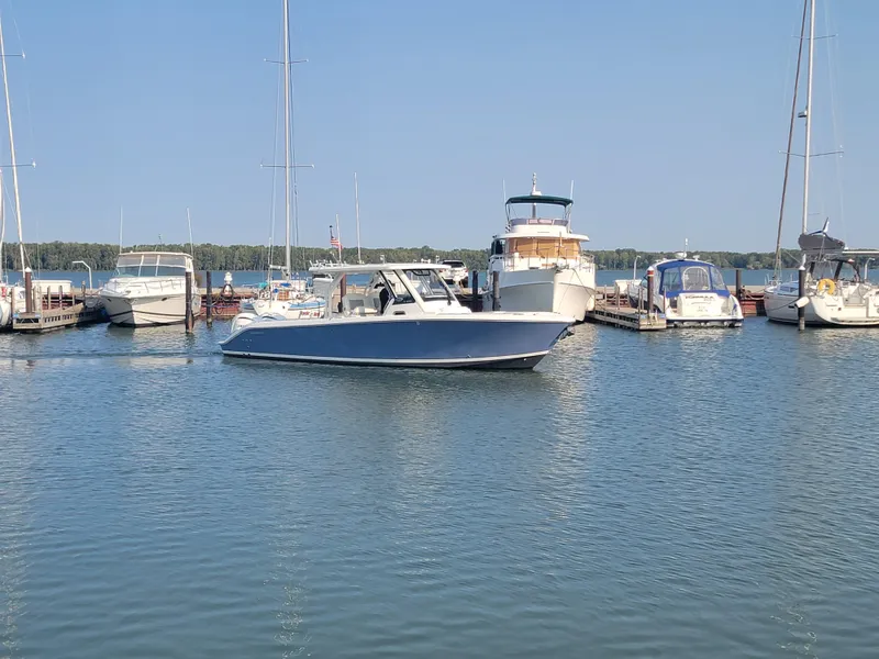 Slide: The Image of 2023 Pursuit S 328 Sport boat docked in a marina with other vessels. - 30
