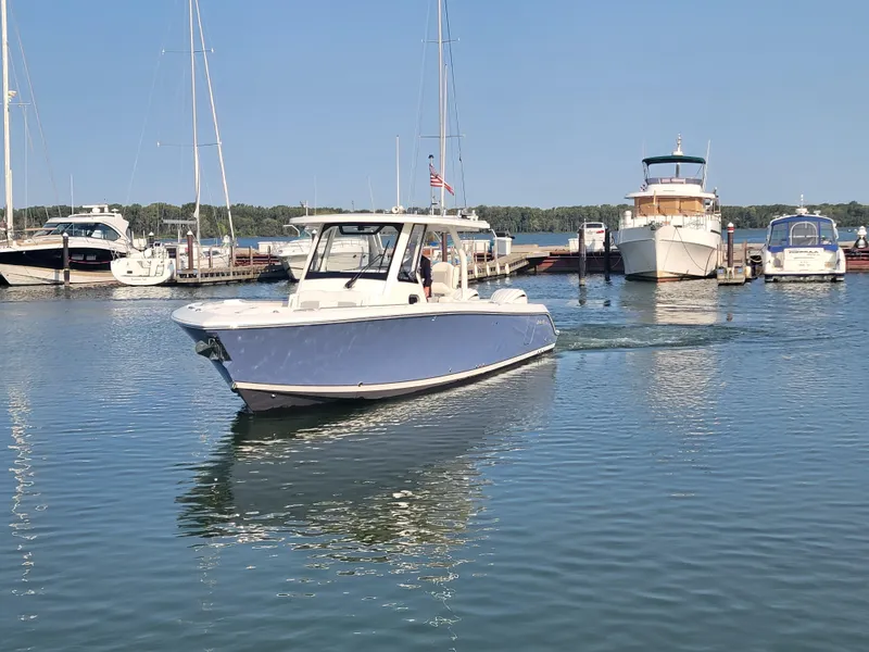 Slide: The Image of 2023 Pursuit S 328 Sport boat cruising in a marina with other vessels. - 31