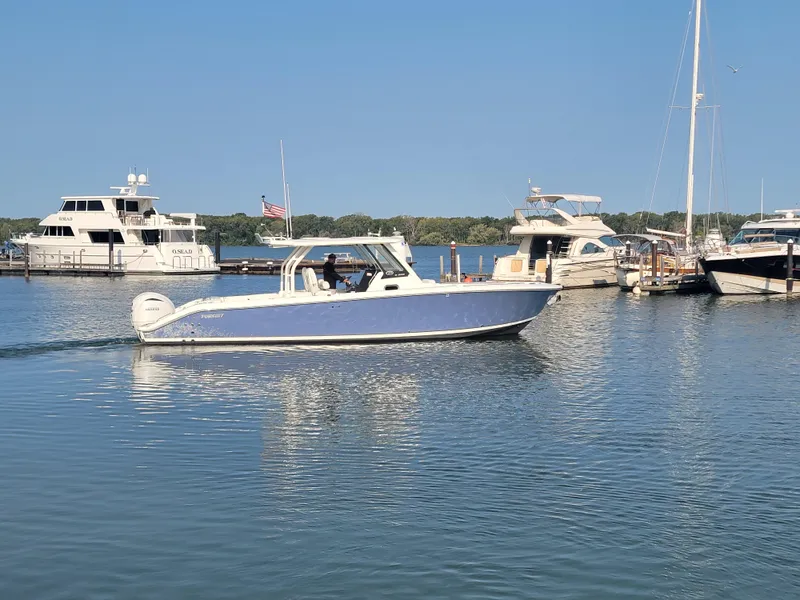 Slide: The Image of 2023 Pursuit S 328 Sport boat cruising in a marina with other yachts. - 32