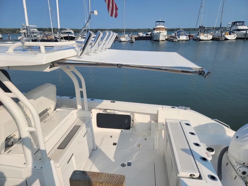 Slide: The Image of 2023 Pursuit S 328 Sport boat docked at marina with extended sunshade. - 49