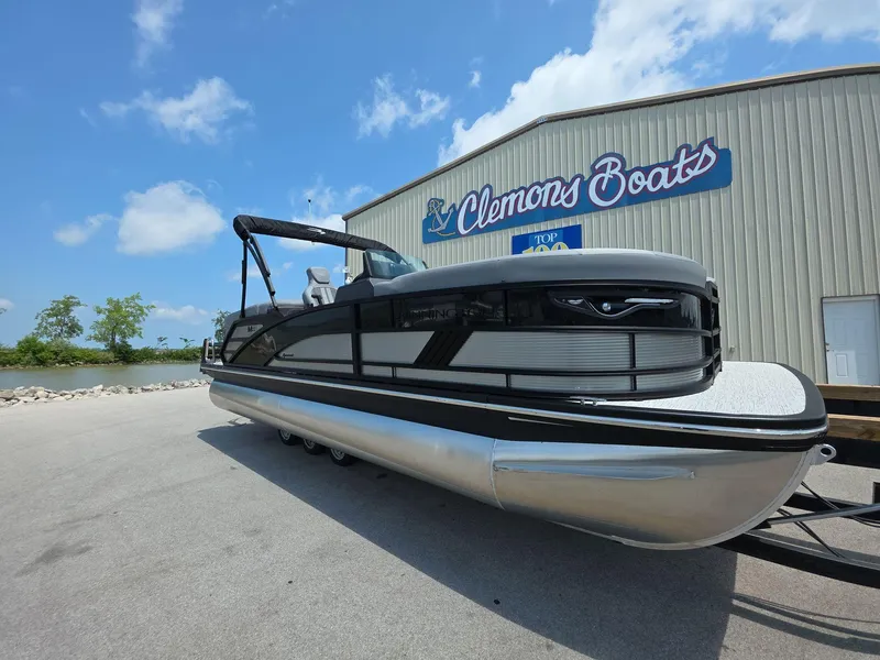 Slide: The Image of 2025 Bennington M Line pontoon boat at Clemons Boats dealership under a blue sky. - 1