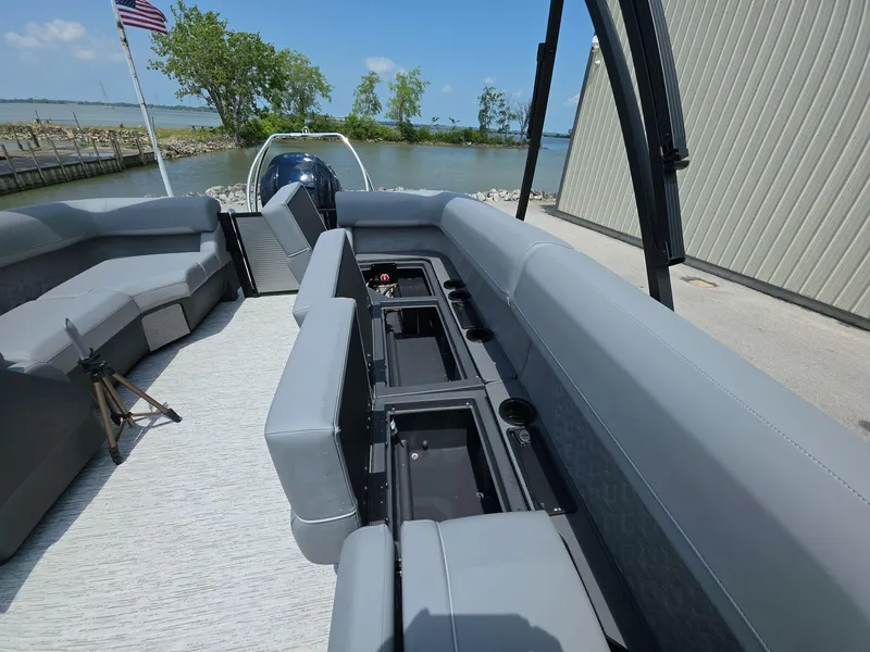 Slide: The Image of 2025 Bennington M Line boat interior with spacious seating and storage, docked by a serene lake. - 10