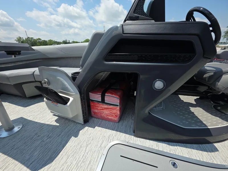 Slide: The Image of 2025 Bennington M Line boat interior with storage compartment and seating, under a clear blue sky. - 17