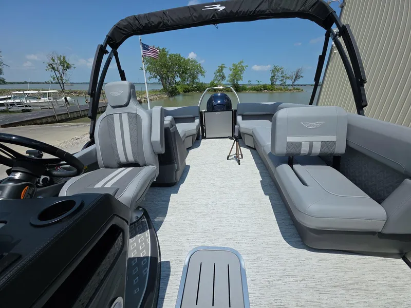 Slide: The Image of 2025 Bennington M Line boat interior with gray seating, steering console, and lake view. - 18