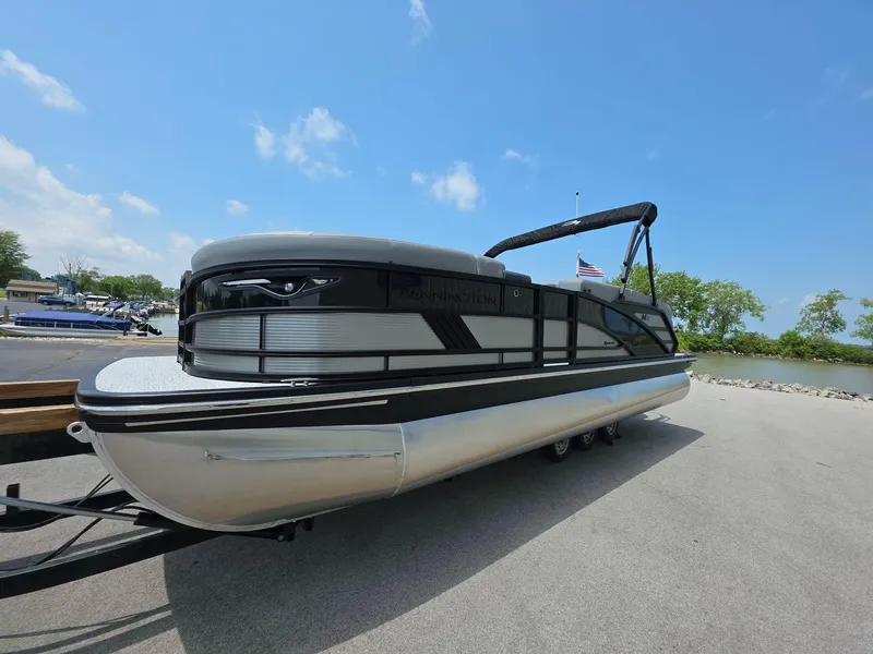 Slide: The Image of 2025 Bennington M Line pontoon boat on trailer under clear blue sky. - 2