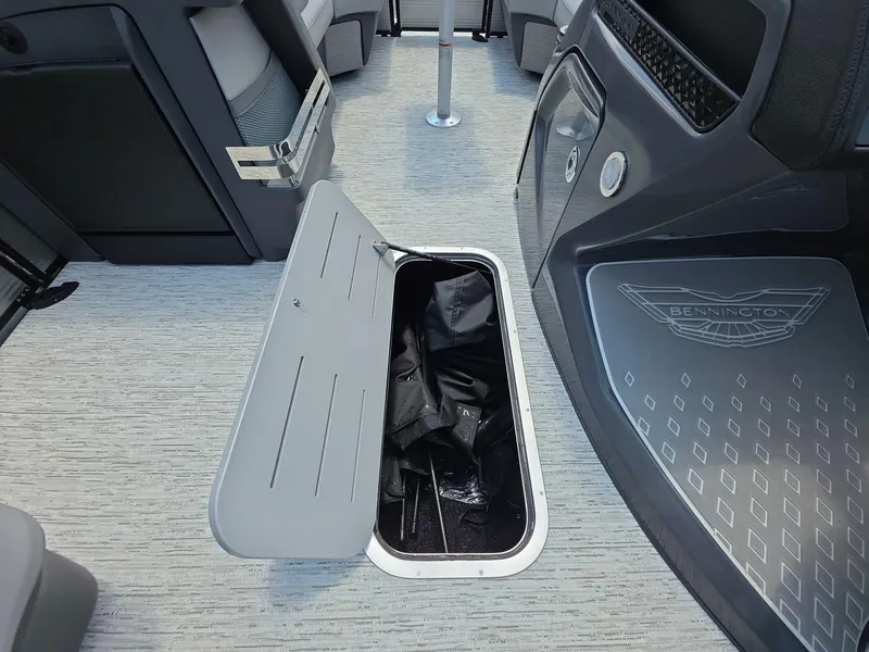 Slide: The Image of 2025 Bennington M Line boat interior with open storage compartment on carpeted floor. - 22