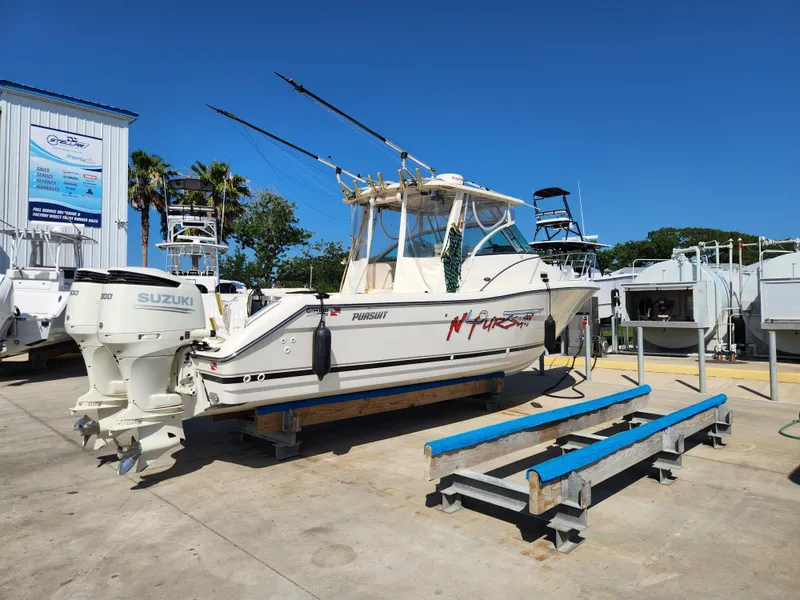 Slide: The Image of 2005 Pursuit 3070 Offshore Center Console boat with Suzuki engines on a trailer. - 3