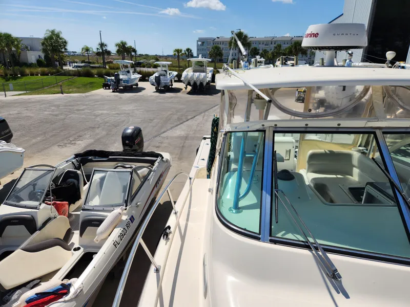 Slide: The Image of 2005 Pursuit 3070 Offshore Center Console boat docked near other boats under a clear sky. - 41
