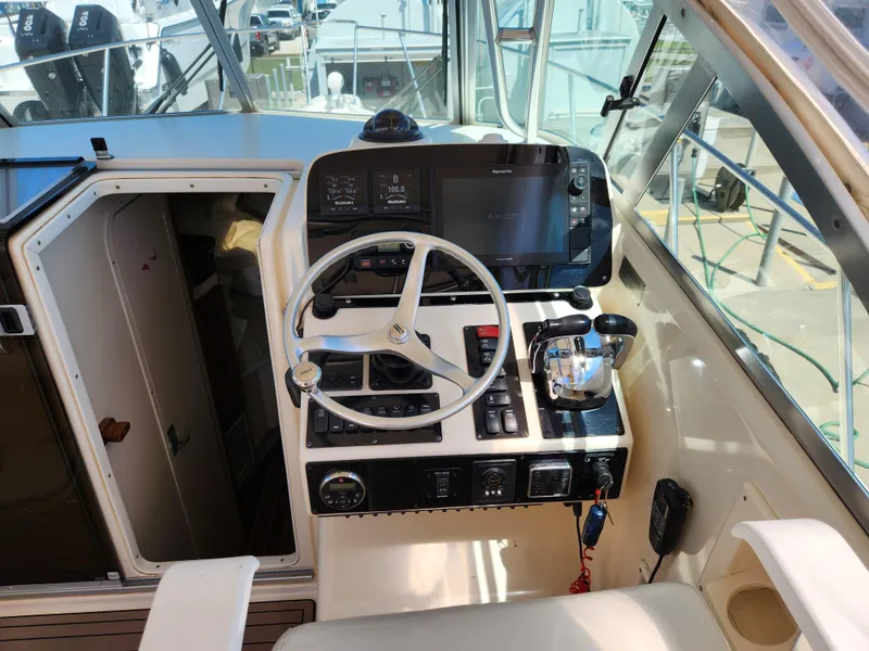 Slide: The Image of 2005 Pursuit 3070 Offshore Center Console helm with steering wheel and navigation controls. - 44