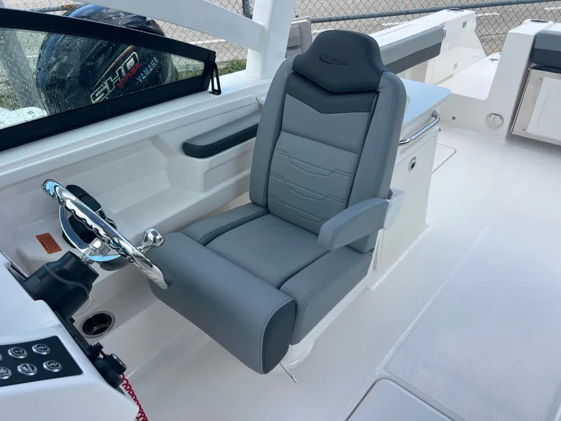 Slide: The Image of 2025 Robalo R257 Dual Console boat interior with gray captain's seat and steering wheel. - 22