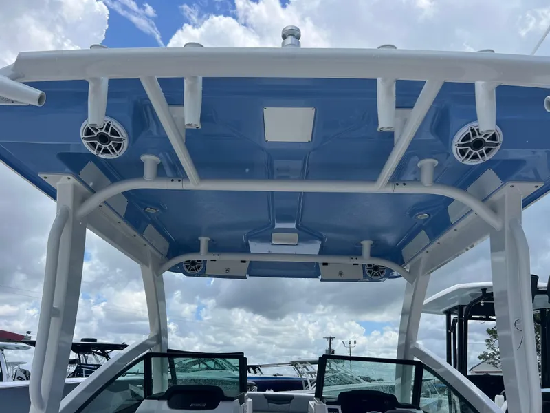 Slide: The Image of 2025 Robalo R257 Dual Console boat with blue canopy and speakers, under a cloudy sky. - 30