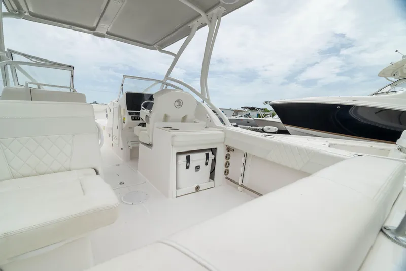 Slide: The Image of 2023 Edgewater 248 CX boat interior with white seating and helm, under a cloudy sky. - 10