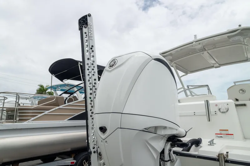 Slide: The Image of 2023 Edgewater 248 CX boat with powerful outboard motor, docked under cloudy sky. - 13