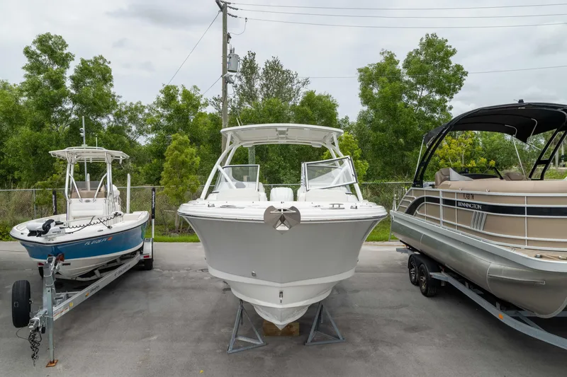 Slide: The Image of 2023 Edgewater 248 CX boat displayed between two other boats in a parking area. - 20