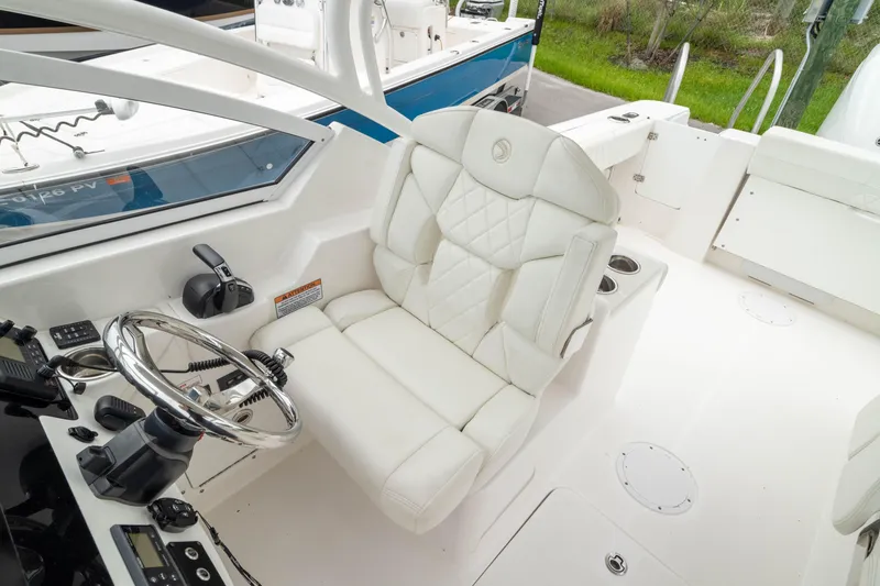 Slide: The Image of 2023 Edgewater 248 CX boat cockpit with white captain's chair and steering wheel. - 34