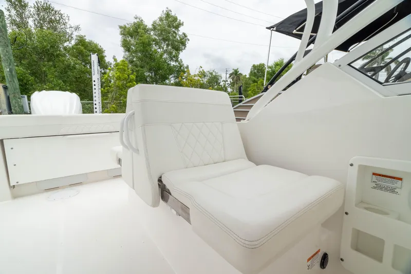 Slide: The Image of 2023 Edgewater 248 CX boat interior with white seating and lush greenery background. - 36
