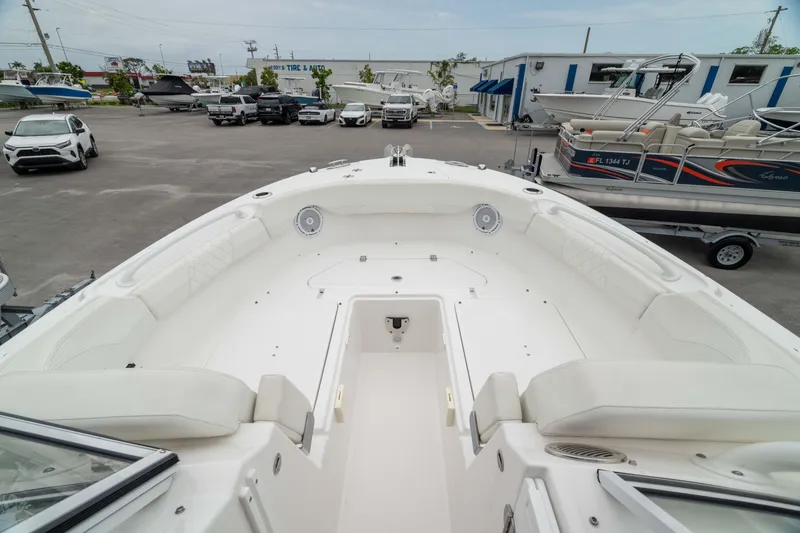 Slide: The Image of 2023 Edgewater 248 CX boat interior with spacious seating, parked in a marina lot. - 38