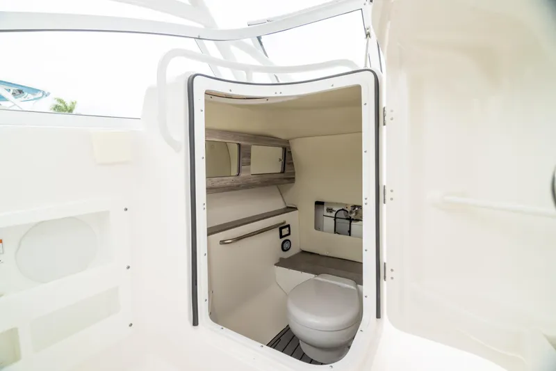 Slide: The Image of 2023 Edgewater 248 CX boat interior with compact marine toilet and storage. - 4