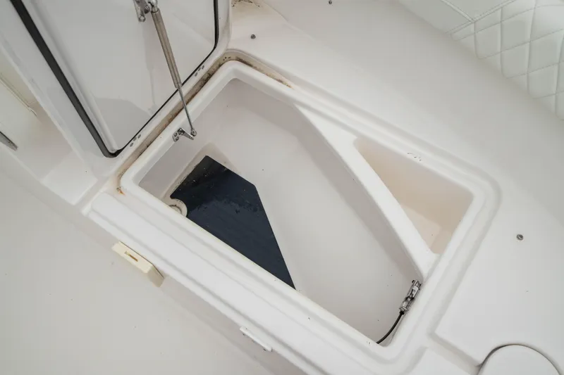 Slide: The Image of 2023 Edgewater 248 CX boat storage compartment, open and empty, with white interior. - 44