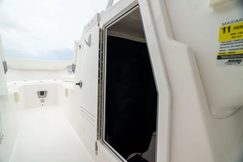 Slide: The Image of 2023 Edgewater 248 CX boat interior with open cabin door, white deck, and safety label. - 47