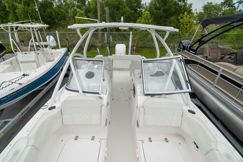 Slide: The Image of 2023 Edgewater 248 CX boat with open deck and seating, docked among other boats. - 49