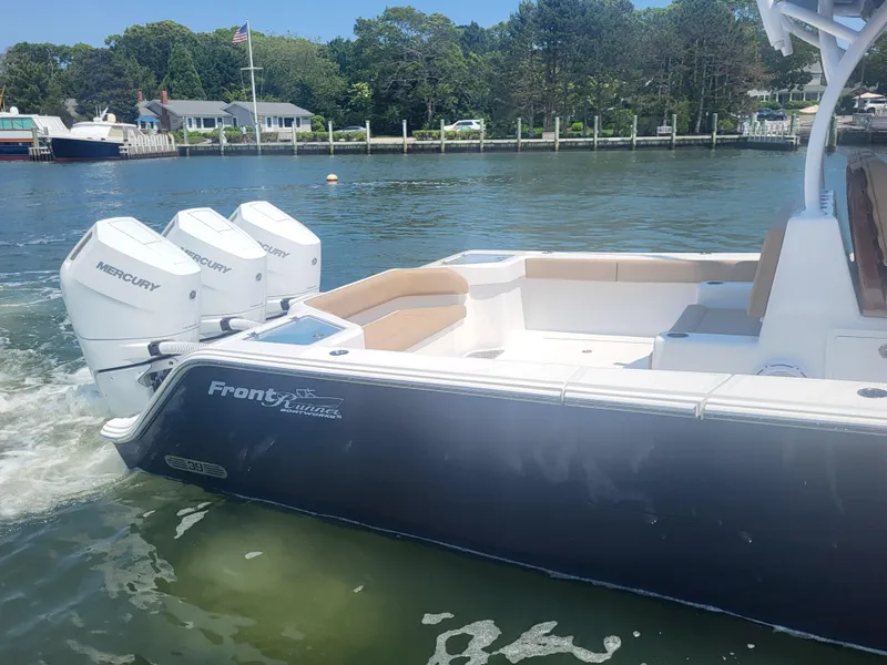 Slide: The Image of 2025 Front Runner 39 boat with triple Mercury engines on a calm waterfront. - 15