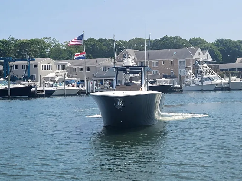 Slide: The Image of Front Runner 39 boat cruising in marina, 2025 model, with buildings and American flag in background. - 23