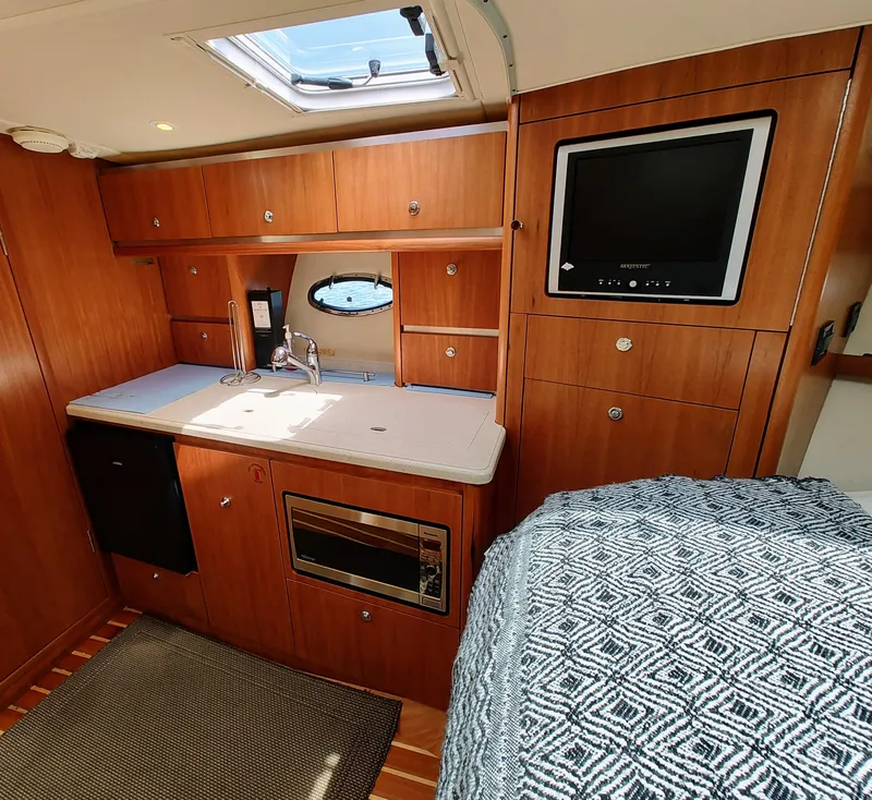 Slide: The Image of Interior of 2008 Tiara Yachts 3200 Open, featuring kitchenette and cozy cabin space. - 30