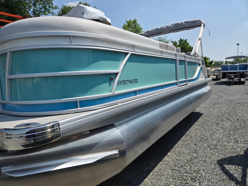 Slide: The Image of 2026 Godfrey SWEETWATER 2286 SB pontoon boat, light blue and white, parked on gravel. - 1