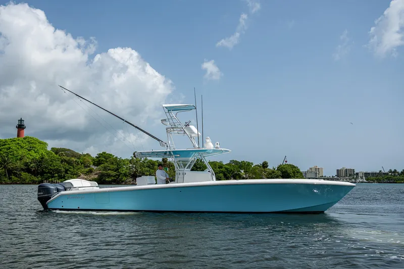 Slide: The Image of 2015 Bahama 41 boat on water, clear sky, lighthouse in background. - 1