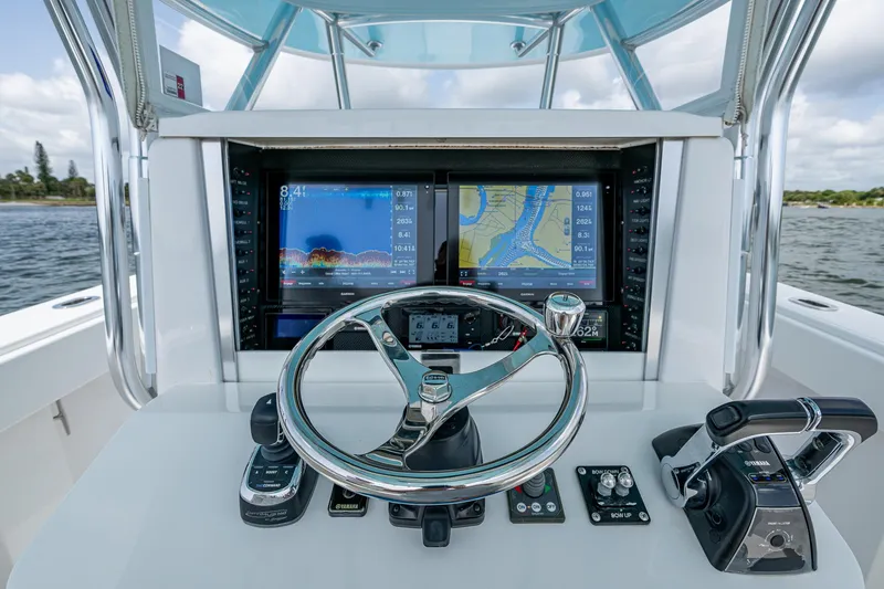 Slide: The Image of Control panel of a 2015 Bahama 41 boat with navigation screens and steering wheel. - 21