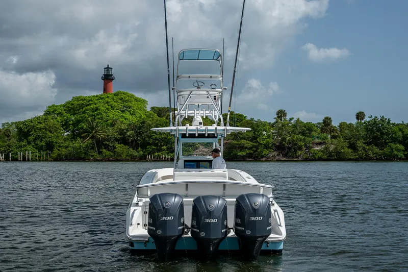 Slide: The Image of 2015 Bahama 41 boat with triple engines on water, lighthouse and greenery in background. - 3