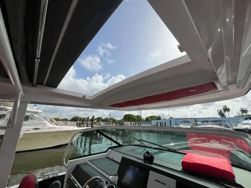 Slide: The Image of 2018 Axopar 37 Sun Top boat interior with open sunroof, docked at marina. - 12