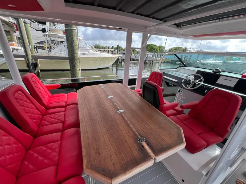 Slide: The Image of 2018 Axopar 37 Sun Top with red seating and wooden table, docked at marina. - 14