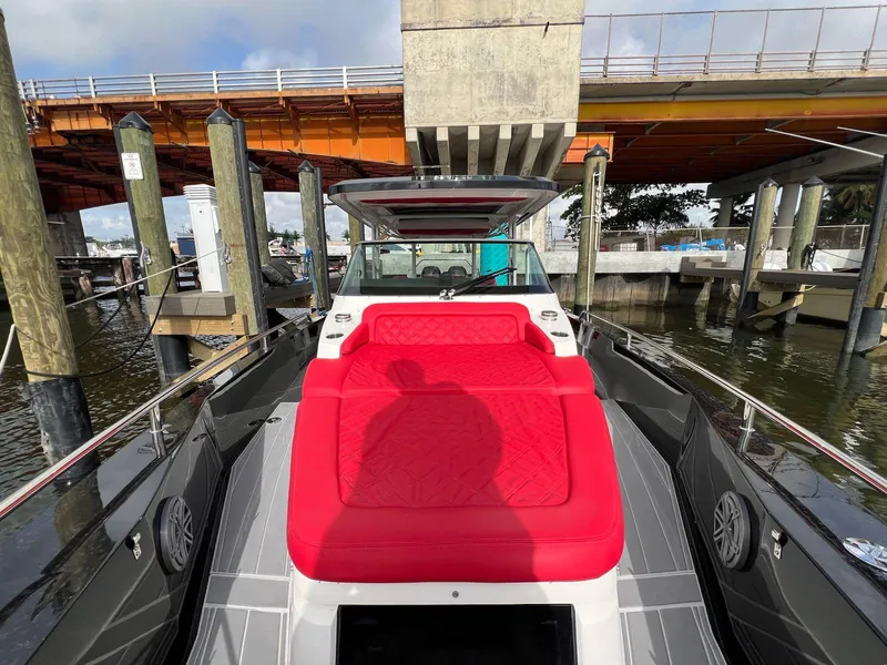 Slide: The Image of 2018 Axopar 37 Sun Top boat with vibrant red seating under a bridge. - 17