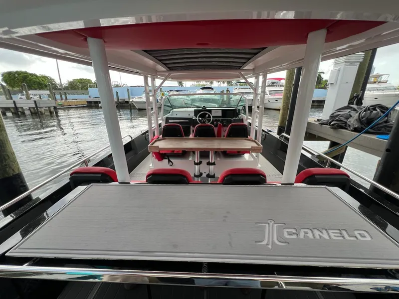 Slide: The Image of 2018 Axopar 37 Sun Top boat interior with seating and table, docked at marina. - 18