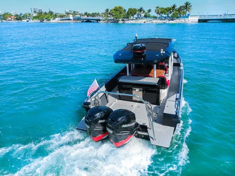 Slide: The Image of 2018 Axopar 37 Sun Top cruising on clear blue water with twin Mercury engines. - 3