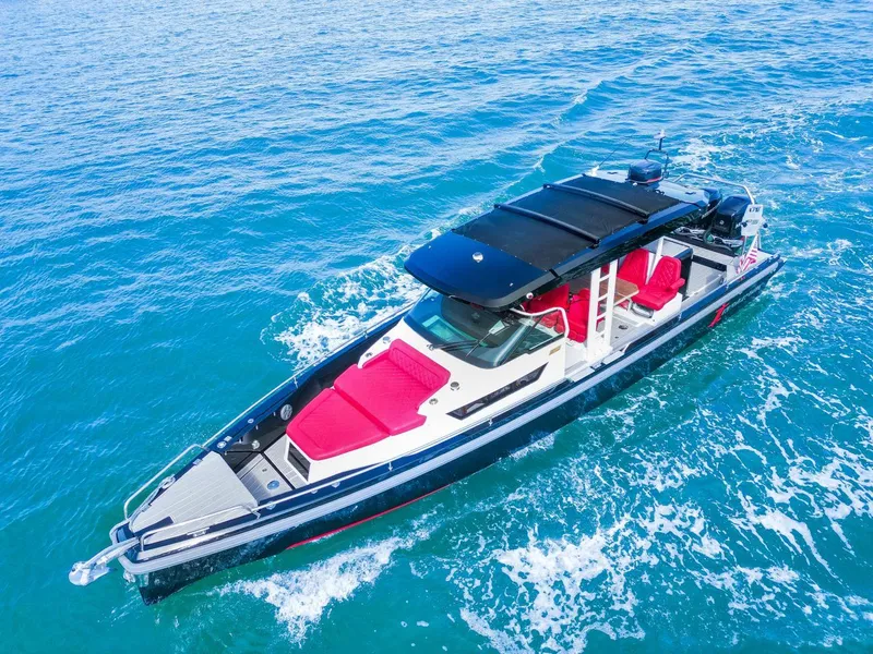 Slide: The Image of 2018 Axopar 37 Sun Top cruising on clear blue water, featuring red seating. - 6