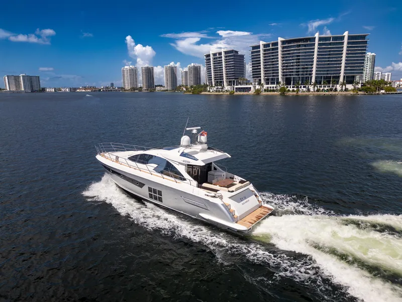 Slide: The Image of 2016 Azimut 55S yacht cruising near modern waterfront buildings under a clear blue sky. - 7