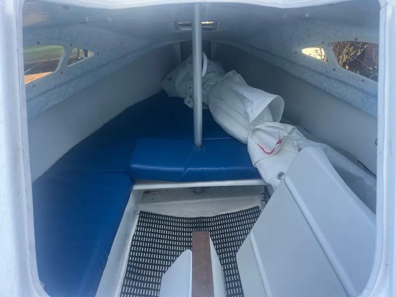 Slide: The Image of Interior of 2023 Malbec 18 sailboat with blue cushions and stored sails. - 4