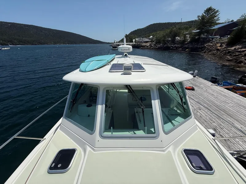 Slide: The Image of 2019 Back Cove Downeast boat docked with a paddleboard on deck, scenic waterway view. - 11