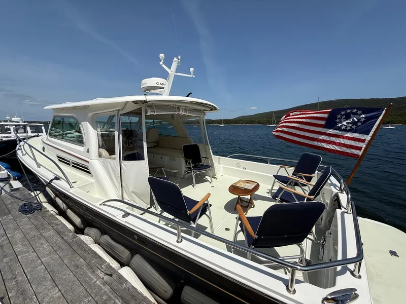 Slide: The Image of 2019 Back Cove Downeast boat docked, featuring seating and a historical American flag. - 13