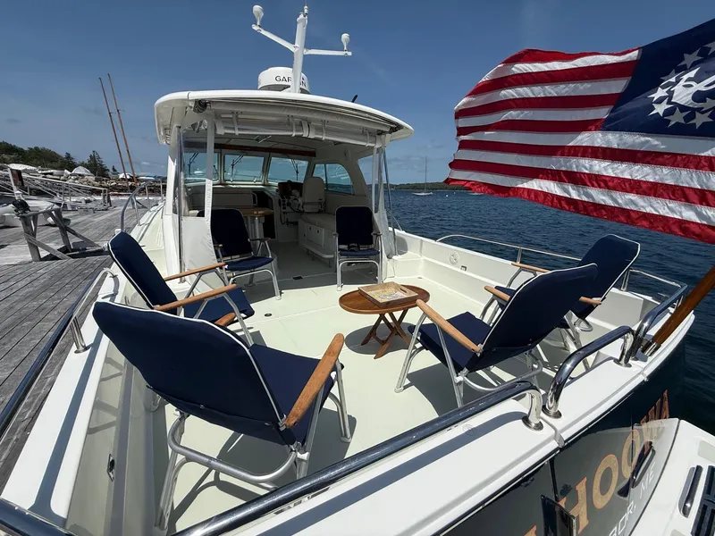Slide: The Image of 2019 Back Cove Downeast boat with seating, American flag, docked by the water. - 14