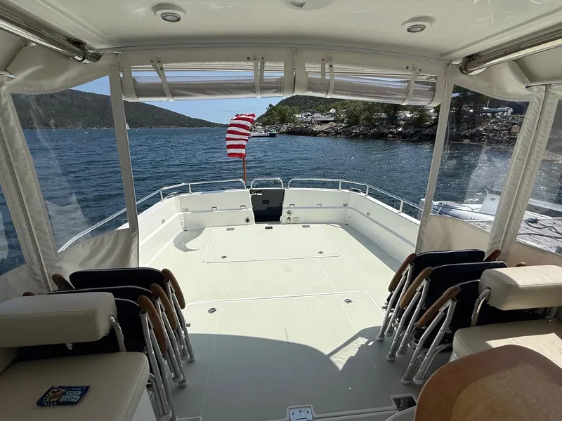 Slide: The Image of 2019 Back Cove Downeast boat interior with seating, open deck, and scenic water view. - 19