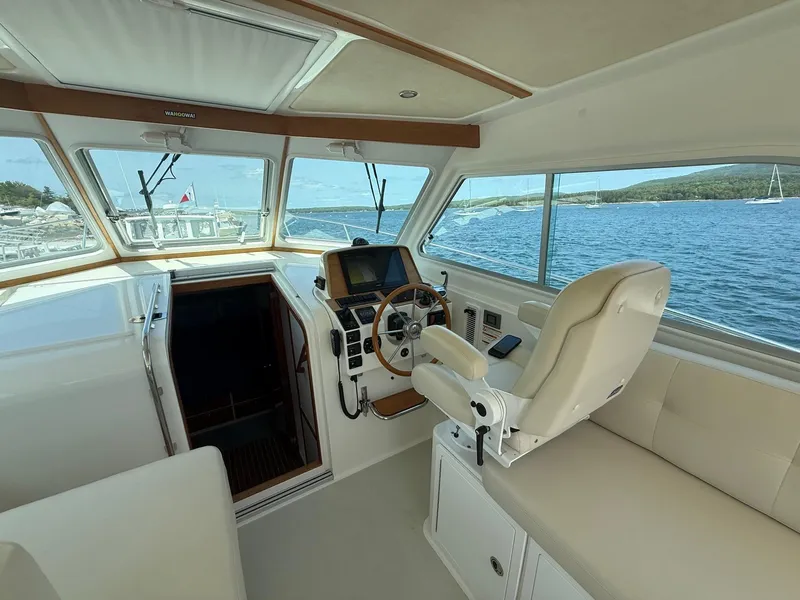 Slide: The Image of 2019 Back Cove Downeast boat interior with helm, steering wheel, and scenic ocean view. - 26