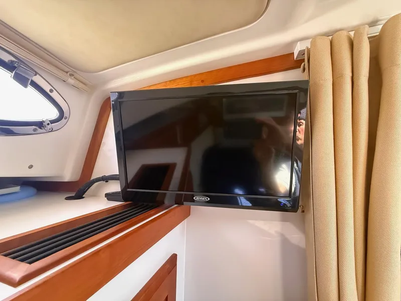 Slide: The Image of Flat-screen TV inside 2019 Back Cove Downeast boat cabin with beige curtains. - 42