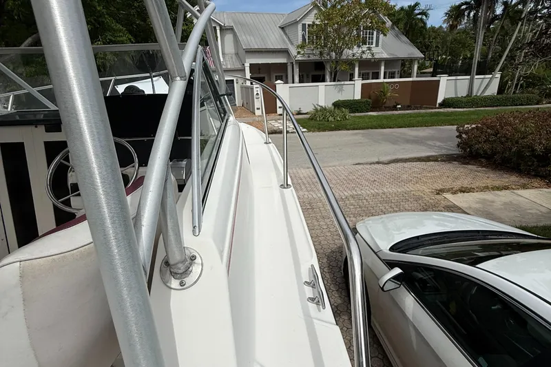 Slide: The Image of 1998 Boston Whaler 23 Conquest boat parked beside a white car in a residential area. - 8